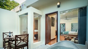 A modern outdoor living area with a dining set, a hot tub, and a view of the interior.