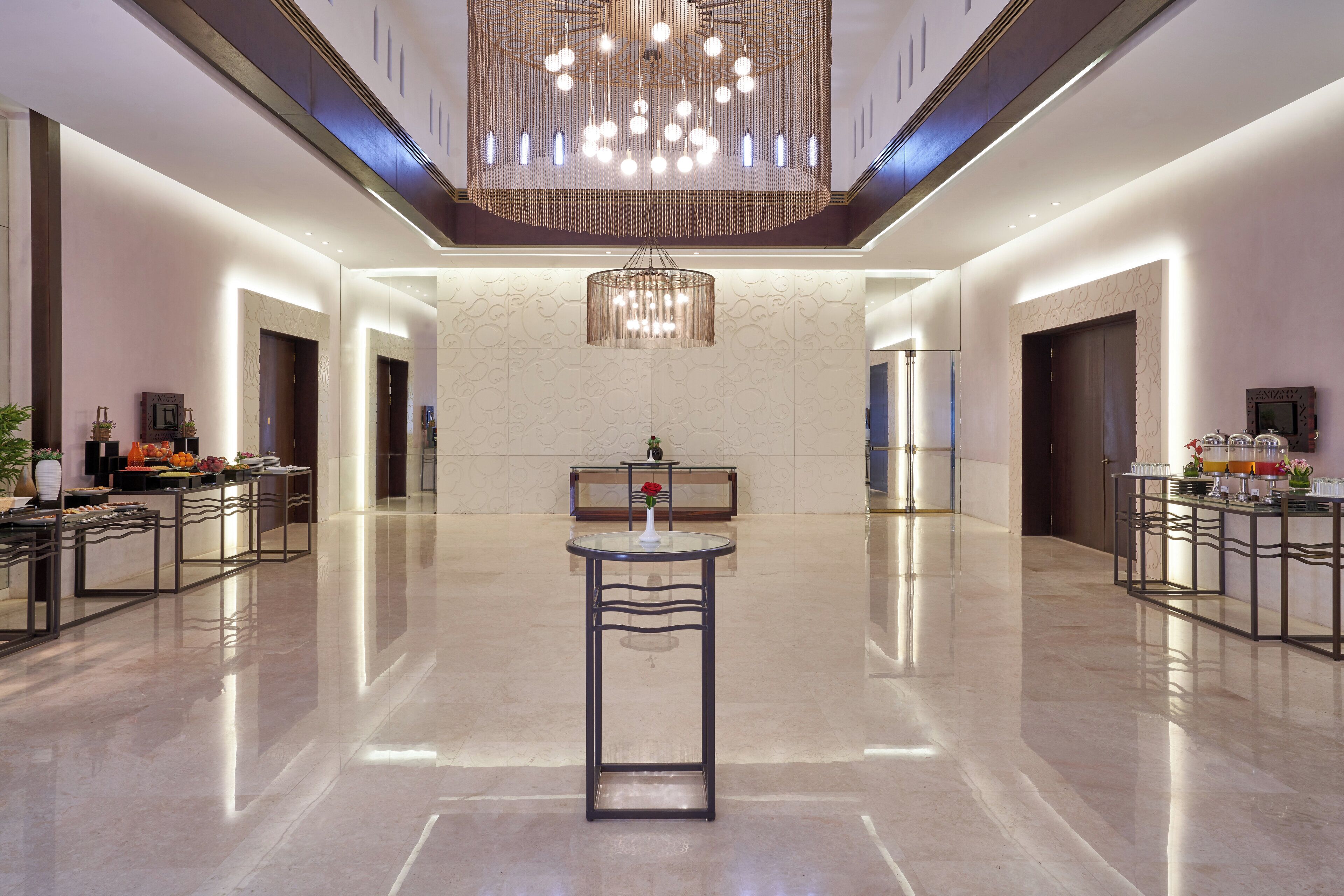 A spacious lobby with a central round table, a chandelier, and a reception desk.