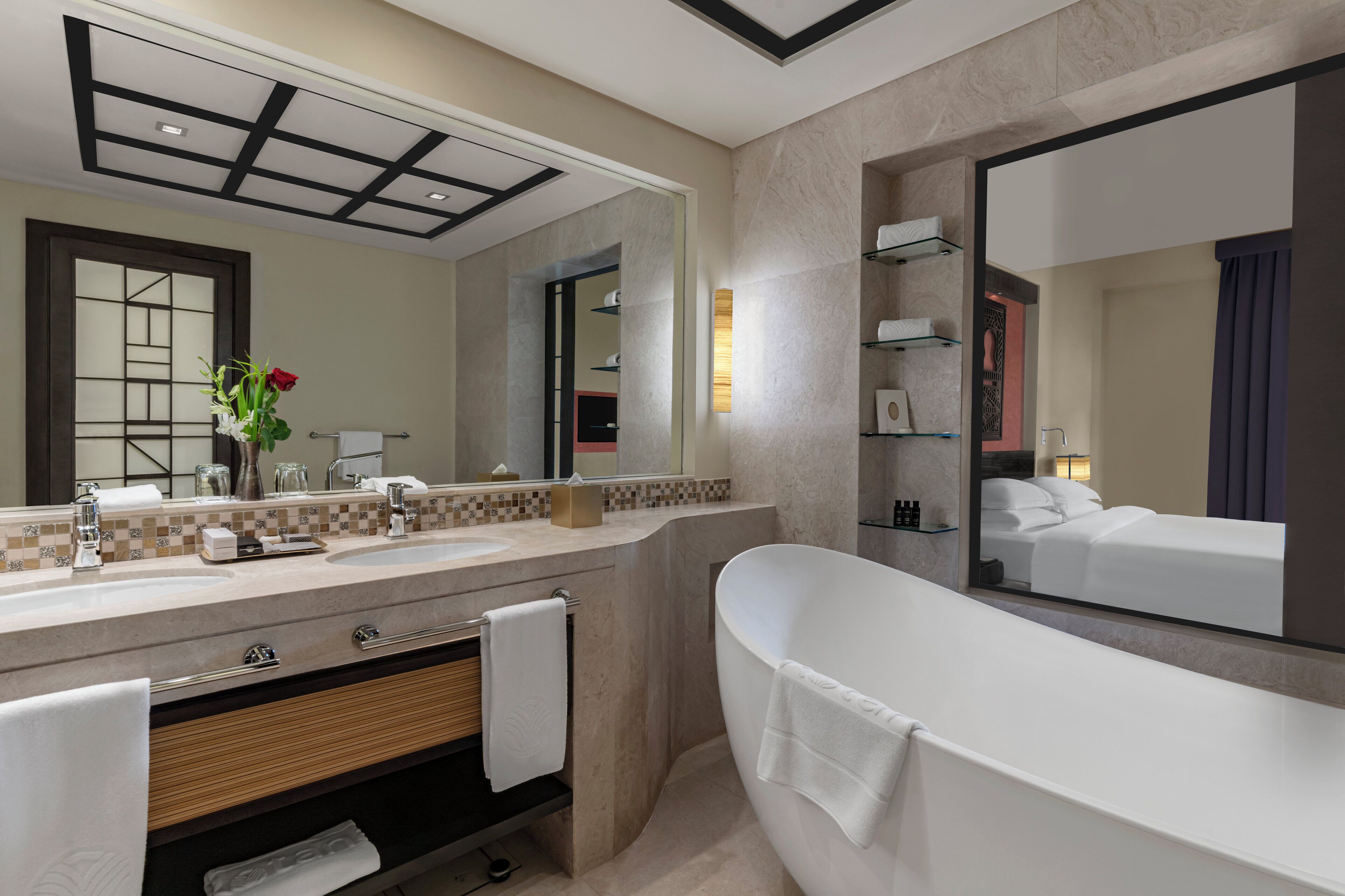 A modern bathroom with a large mirror, a bathtub, a vanity with a sink, and a shower area.