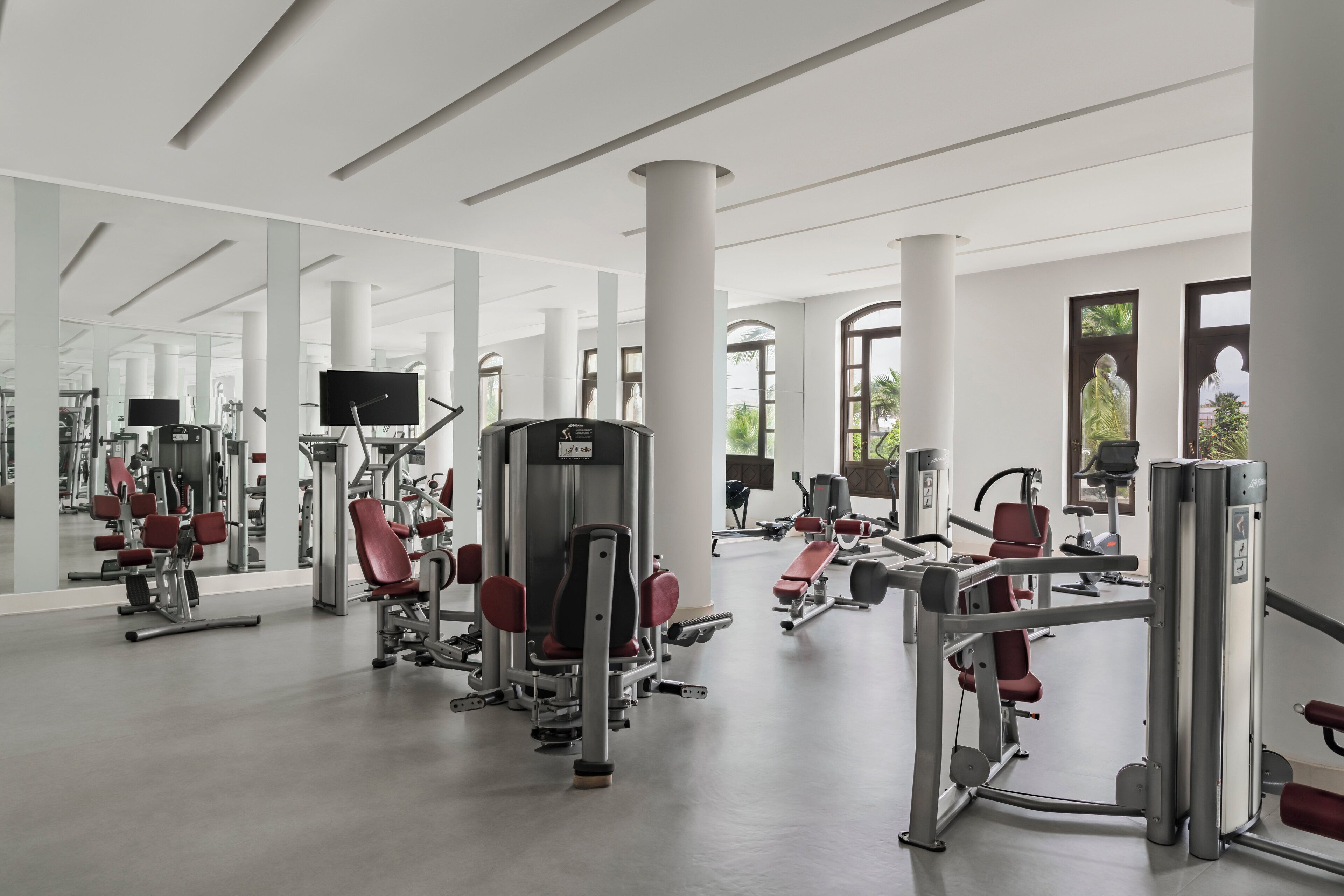 Ett modernt gym med olika träningsmaskiner, stora speglar och en rymlig planlösning.