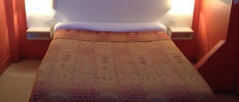 A bedroom with a bed, two bedside tables, and a sloped ceiling.