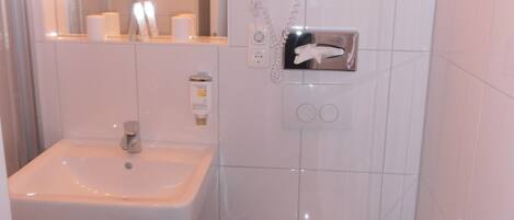 A bathroom with a sink, mirror, toilet, and shower.