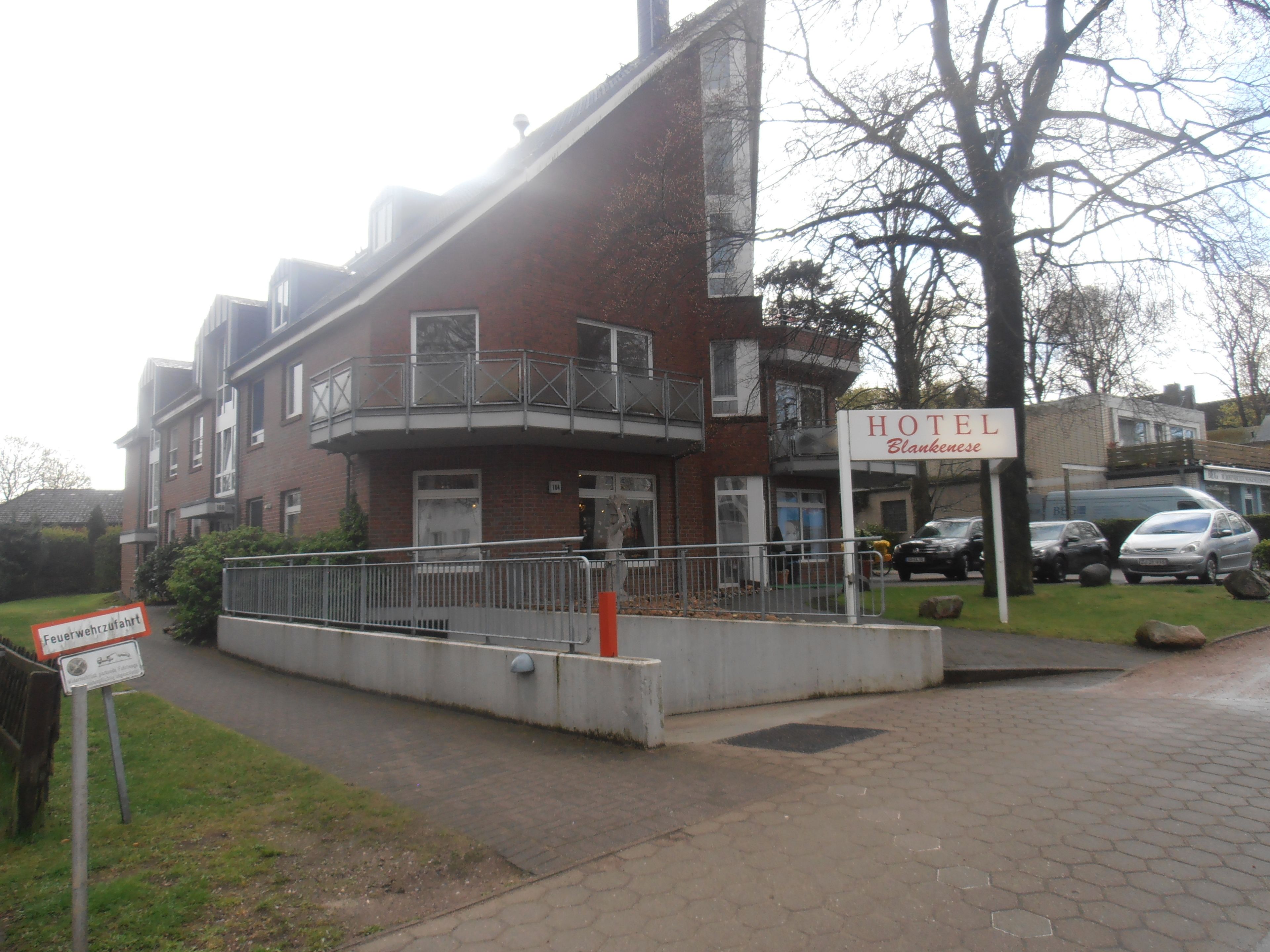 Un hôtel avec une enseigne indiquant « HÔTEL Blankensee » et un panneau signalant la présence d’une borne d’incendie à proximité.
