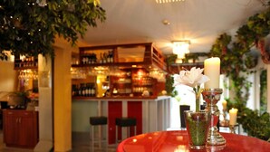 A bar area with a red table, a candle, and a flower arrangement. - Hotel Blankenese (Hamburg)