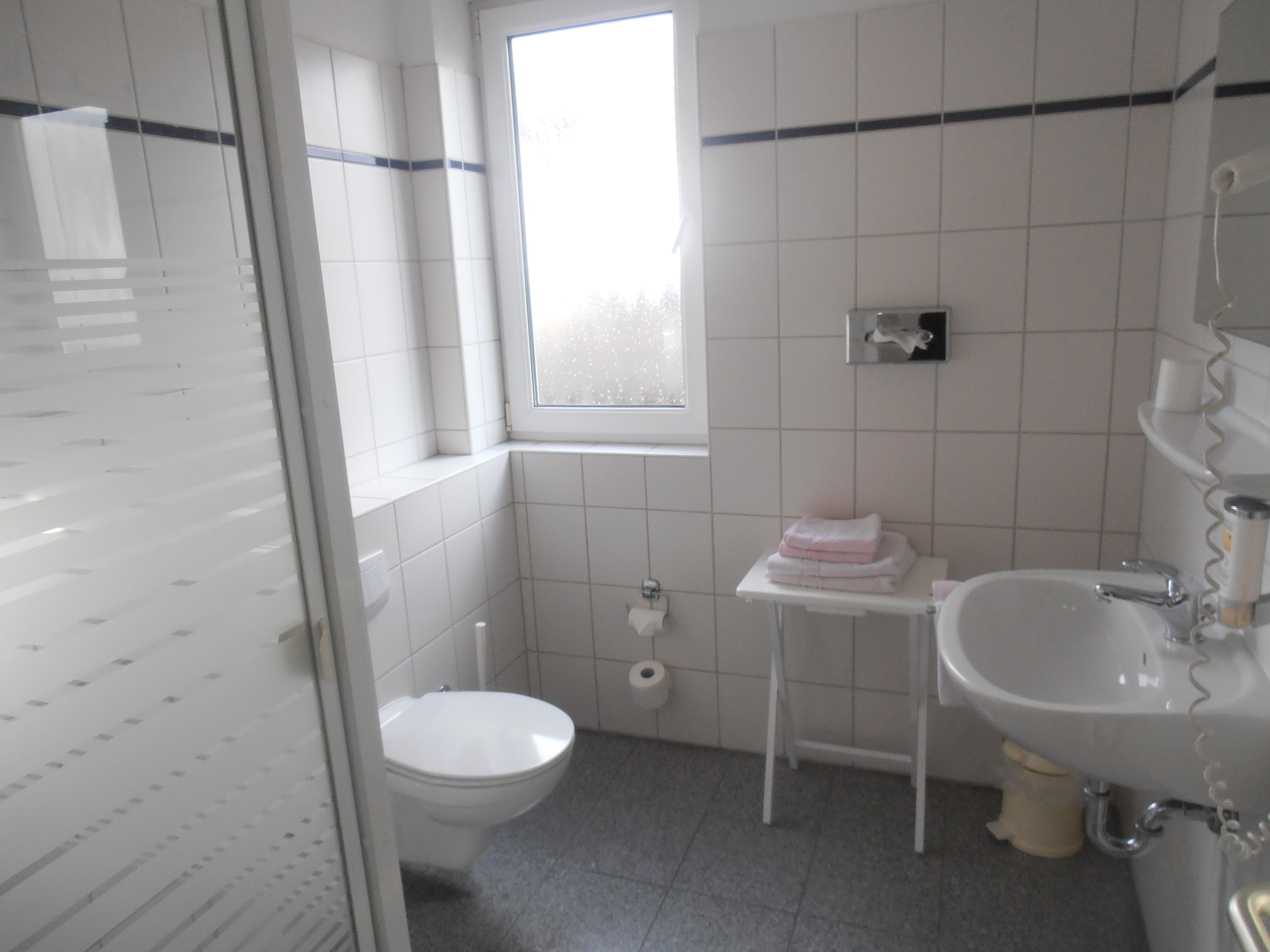 A bathroom with a toilet, sink, and a small window.