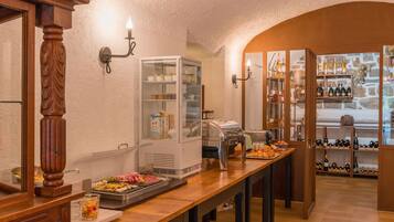 A buffet setup with a glass display case, a buffet station with food, and wine shelves.