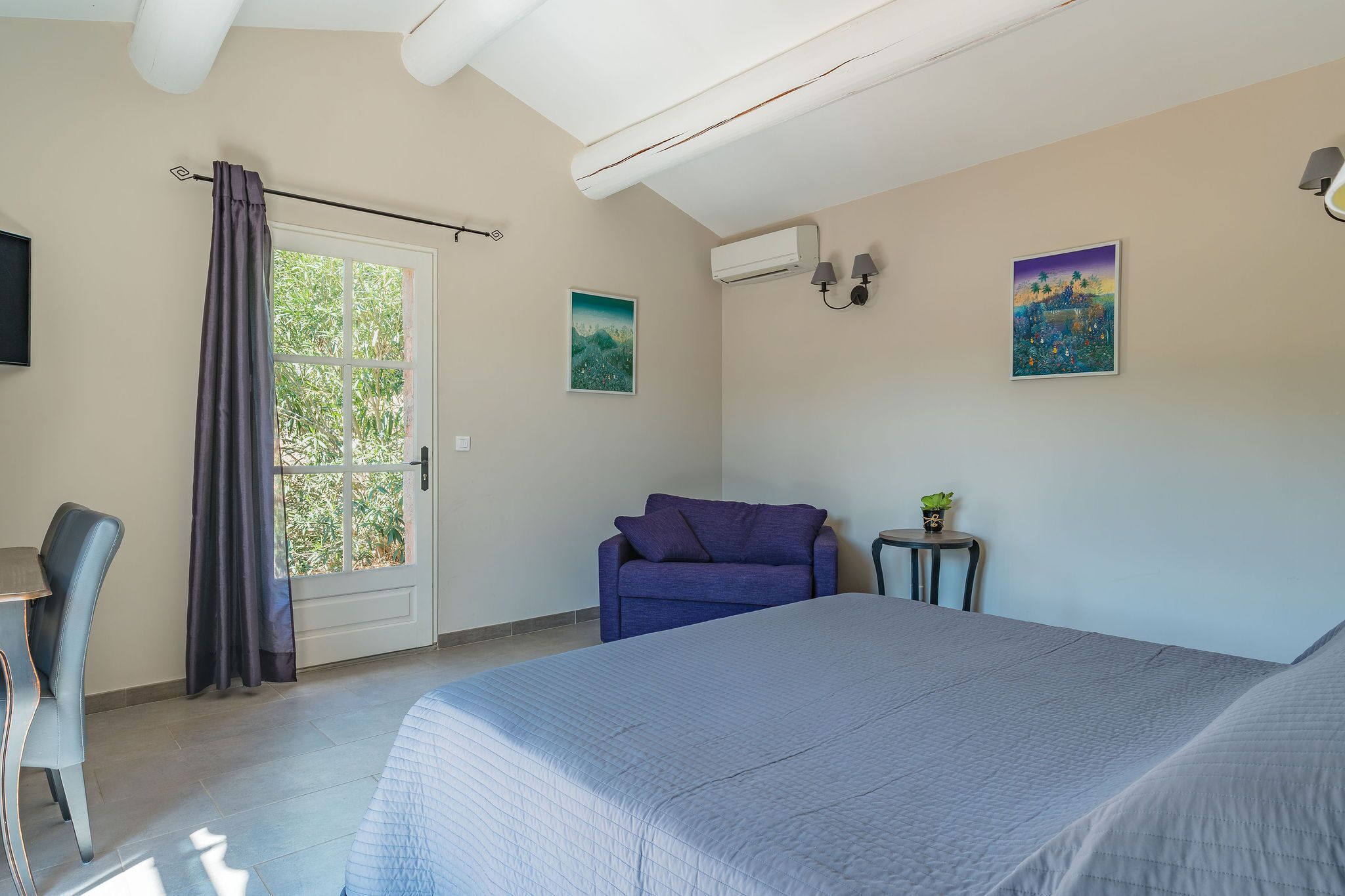 A bedroom with a bed, a sofa, a desk, and a window with curtains.