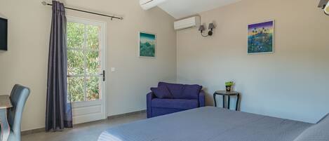 A bedroom with a bed, a sofa, a desk, and a window with curtains.