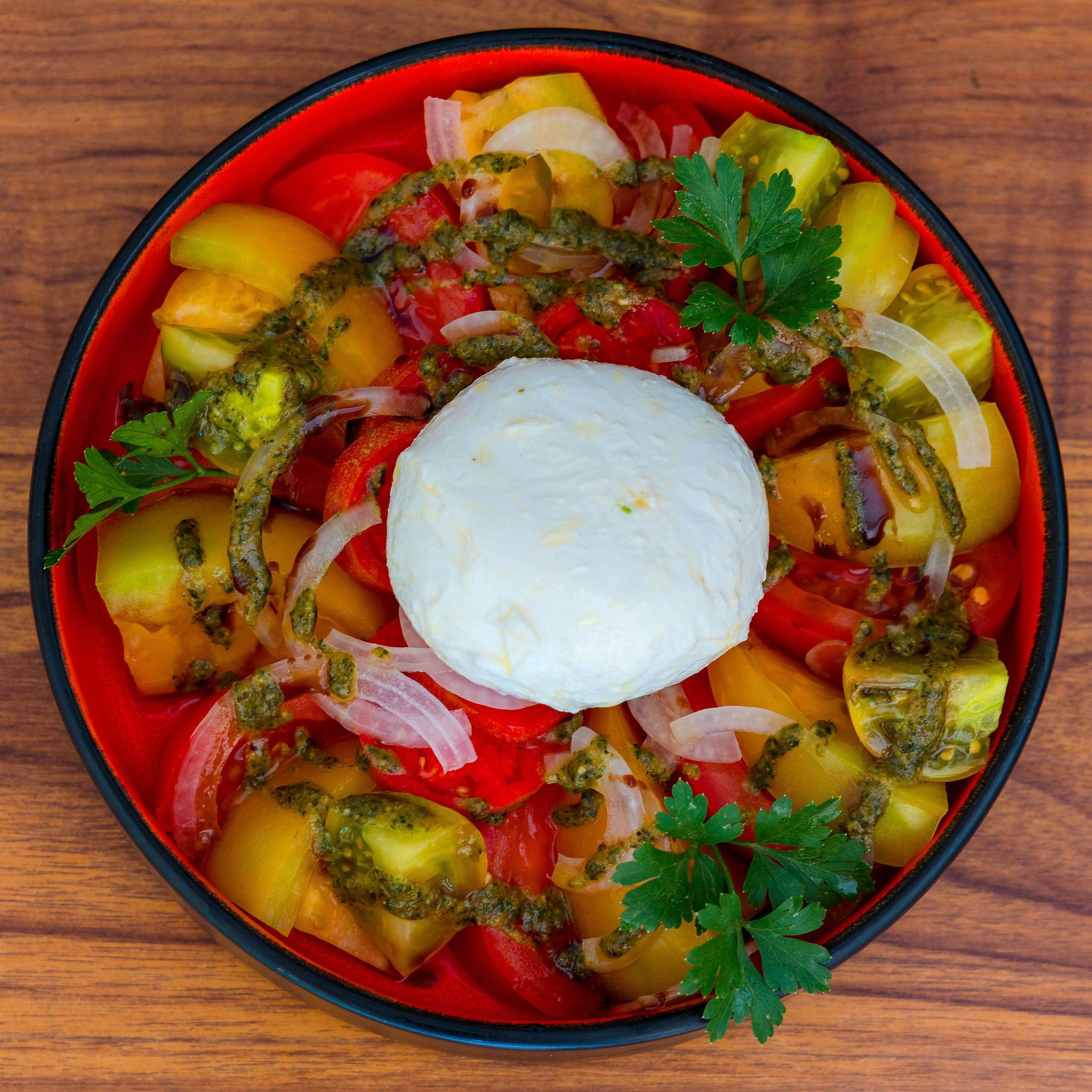Un tazón de ensalada con diversos vegetales y una cucharada de crema en el centro.