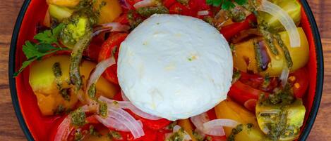 Un tazón de ensalada con diversos vegetales y una cucharada de crema en el centro.