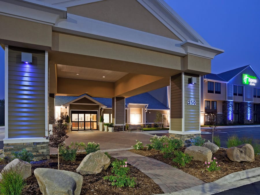 A Holiday Inn Express & Suites hotel with a covered entrance, outdoor seating, and a landscaped garden.