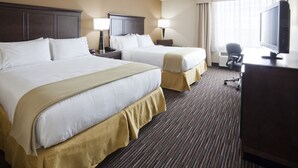 A hotel room with two beds, a desk with a computer, a TV, and a window with curtains.