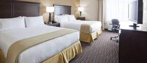 A hotel room with two beds, a desk with a computer, a TV, and a window with curtains.
