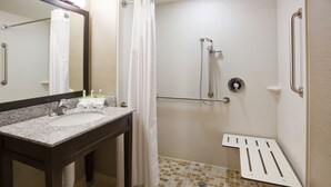 A bathroom with a sink, mirror, shower, and grab bars.