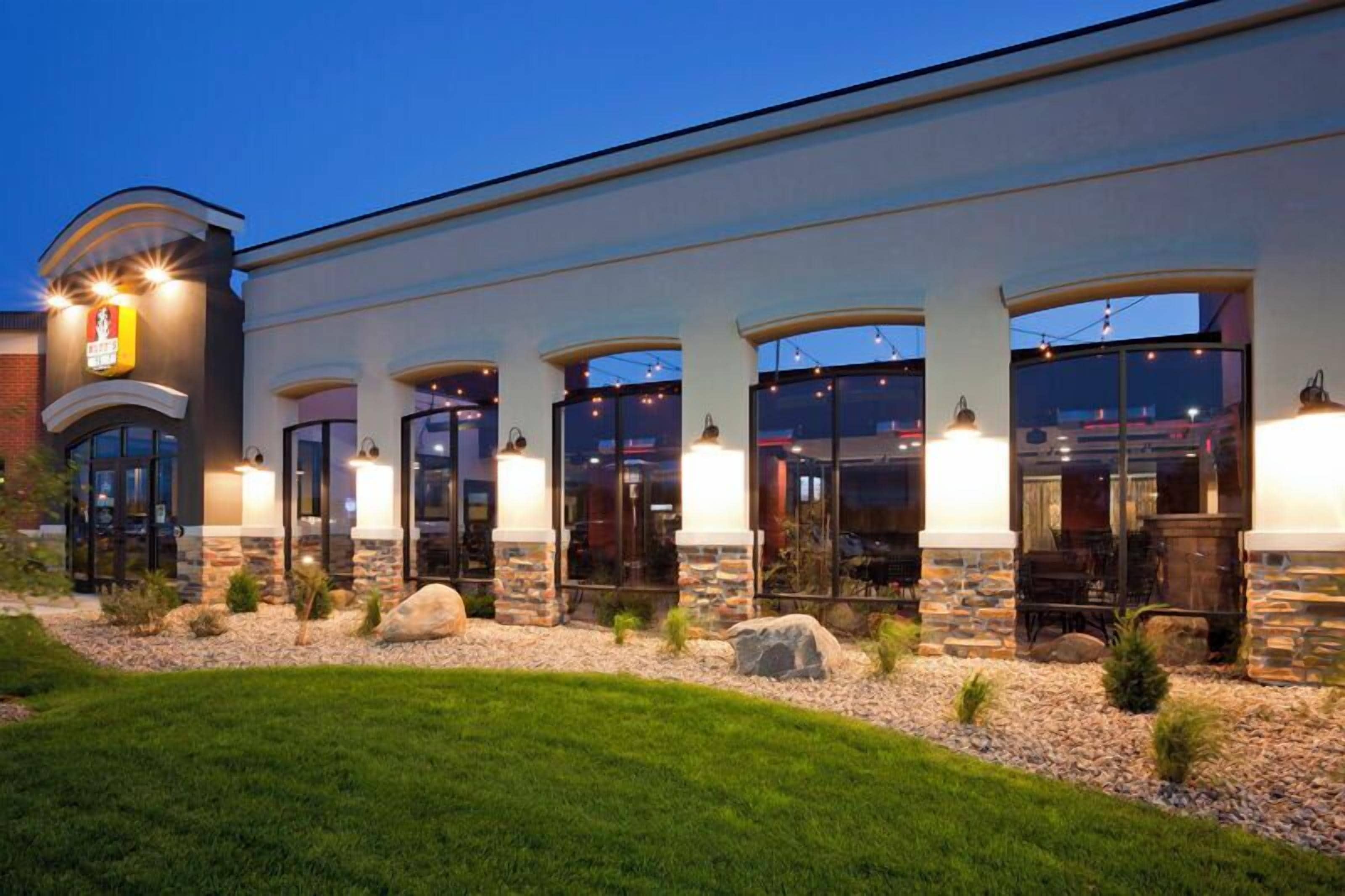 A building with a stone facade, multiple entryways, and outdoor seating areas.