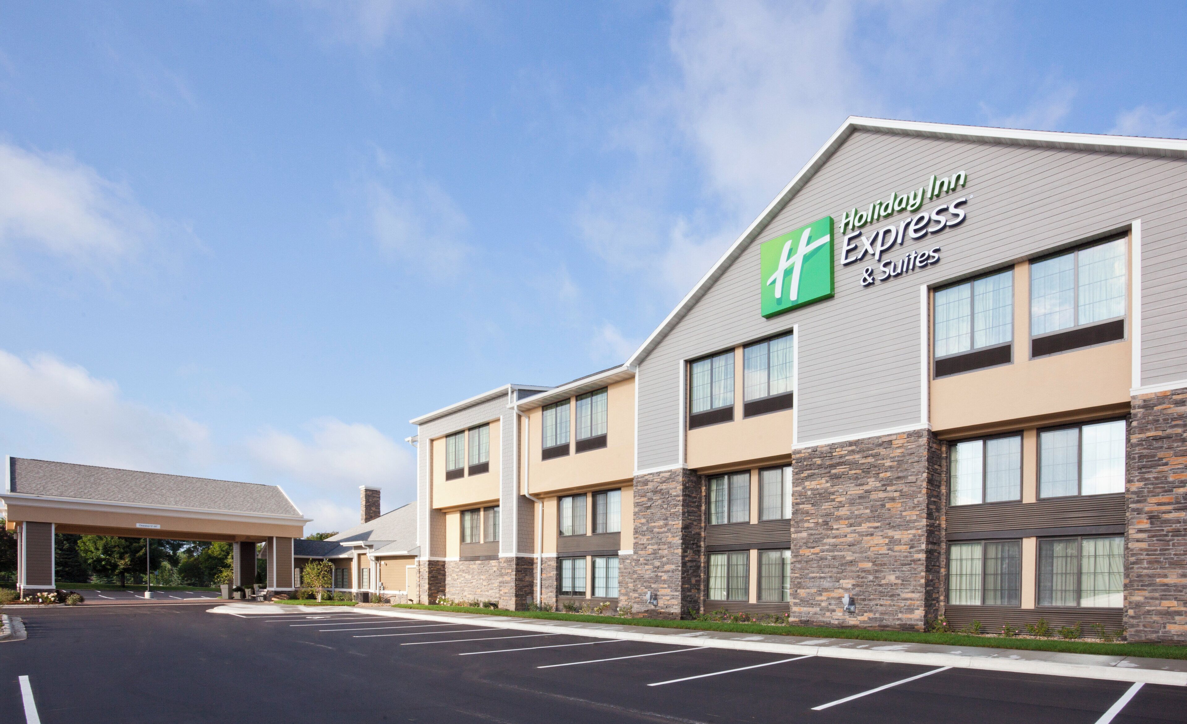A Holiday Inn Express & Suites hotel with a modern design, featuring a parking lot and a covered entrance.