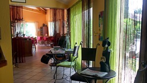 A dining area with green curtains, a table with a newspaper, and chairs. - Hôtel du Vieux Moulin (Gignac)