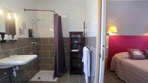 A bathroom with a shower, sink, and a small shelf with toiletries. - Hôtel du Vieux Moulin (Gignac)