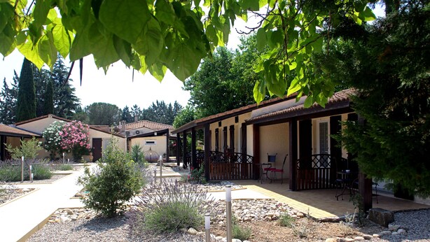 A courtyard with a pathway, outdoor seating, and a building with a tiled roof. - Hôtel du Vieux Moulin (Gignac)
