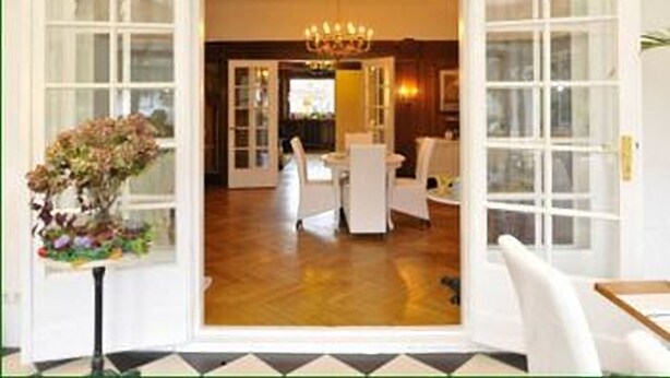 An open door leading to a dining area with white furniture and a chandelier. - Hotel Schmidt (Hamburg)