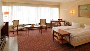 A hotel room with a bed, two chairs, a small table, a desk, and a lamp. - Hotel Schmidt (Hamburg)