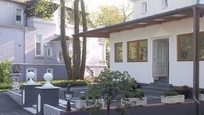 A two-story house with a front porch, a small garden, and a pathway leading to the entrance. - Hotel Schmidt (Hamburg)