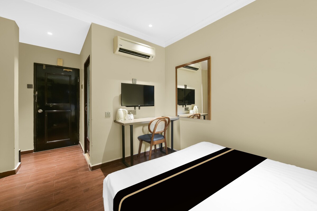 Ein Hotelzimmer mit einem Bett, einem Schreibtisch mit Stuhl, einem Fernseher, einer Klimaanlage und einer Tür.