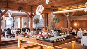 Una mesa de madera con diversos alimentos en un ambiente rústico, con vigas a la vista y paredes de piedra.