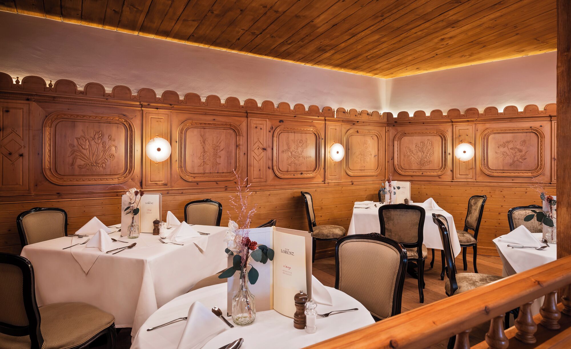 A dining area with wooden paneling and white tablecloths.