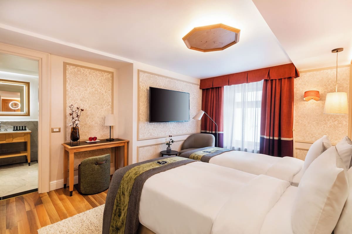 Ett hotellrum med en säng, ett skrivbord, en stol, en tv och en spegel.