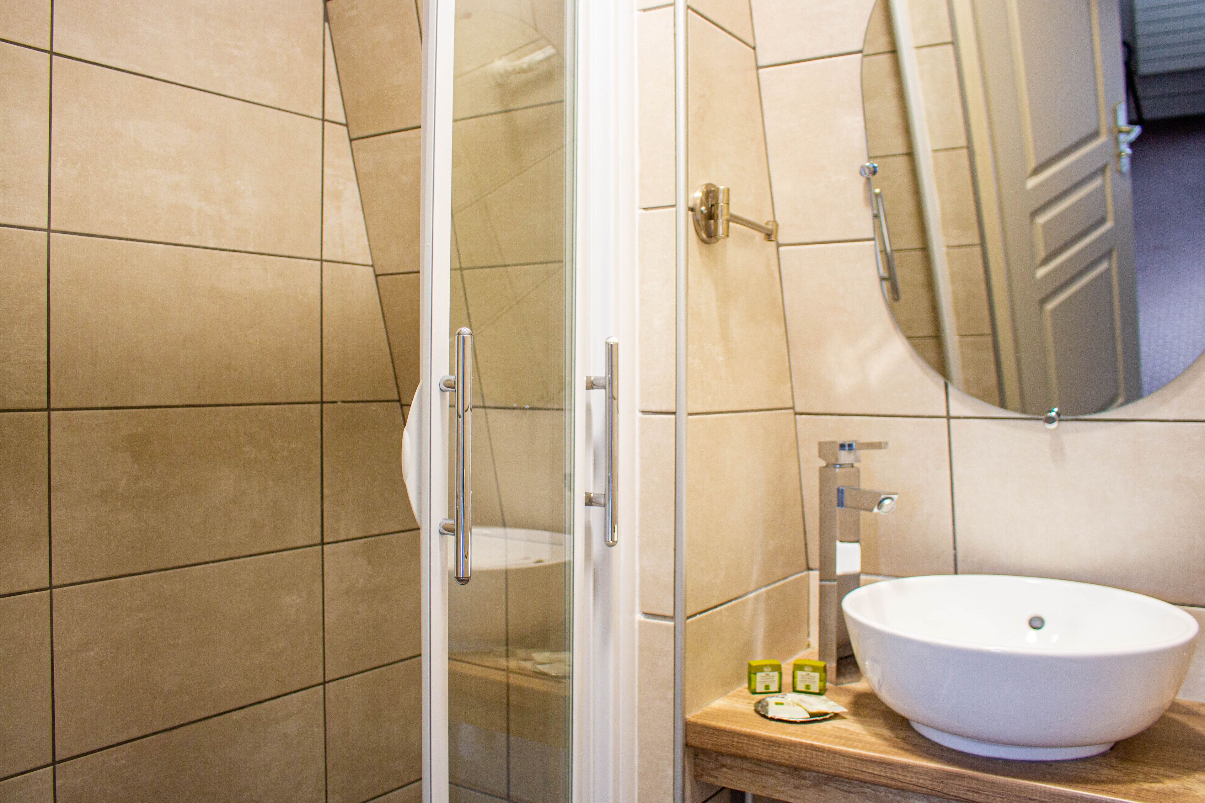 A bathroom with a glass shower enclosure, a white sink, and a mirror above it.