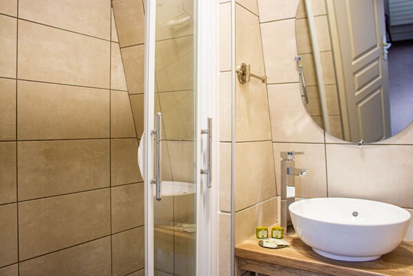 Un baño con cabina de ducha de vidrio, un lavabo blanco y un espejo encima.