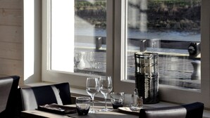 A dining table with a view of a body of water through a window, a wicker basket, and empty wine glasses. - Hôtel du Port et des bains (Saint-Valery-sur-Somme)
