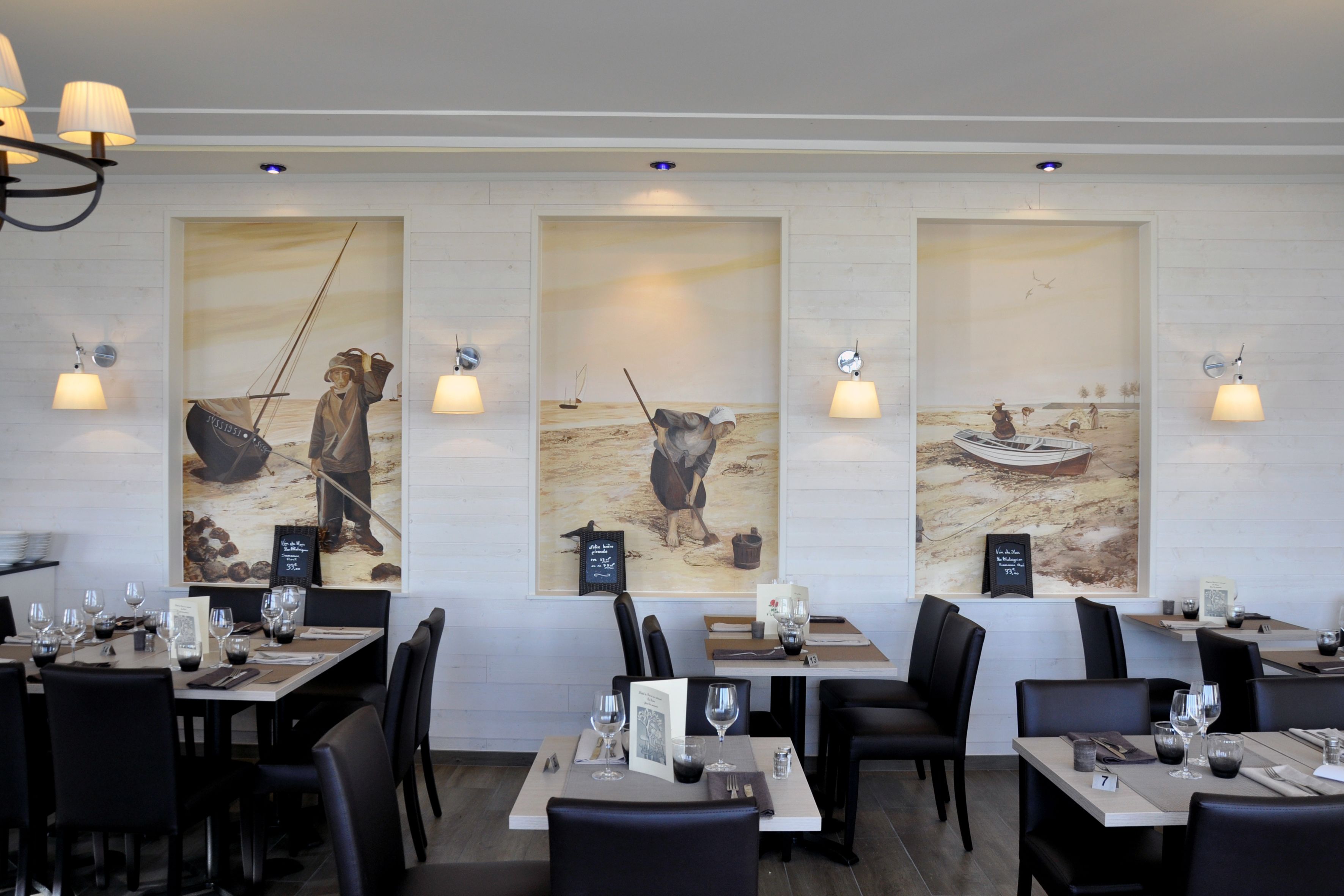 A restaurant interior with tables set for dining, artwork on the walls, and ambient lighting.