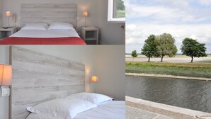 A bedroom with a wooden headboard, two bedside lamps, and a view of a canal with trees. - Hôtel du Port et des bains (Saint-Valery-sur-Somme)
