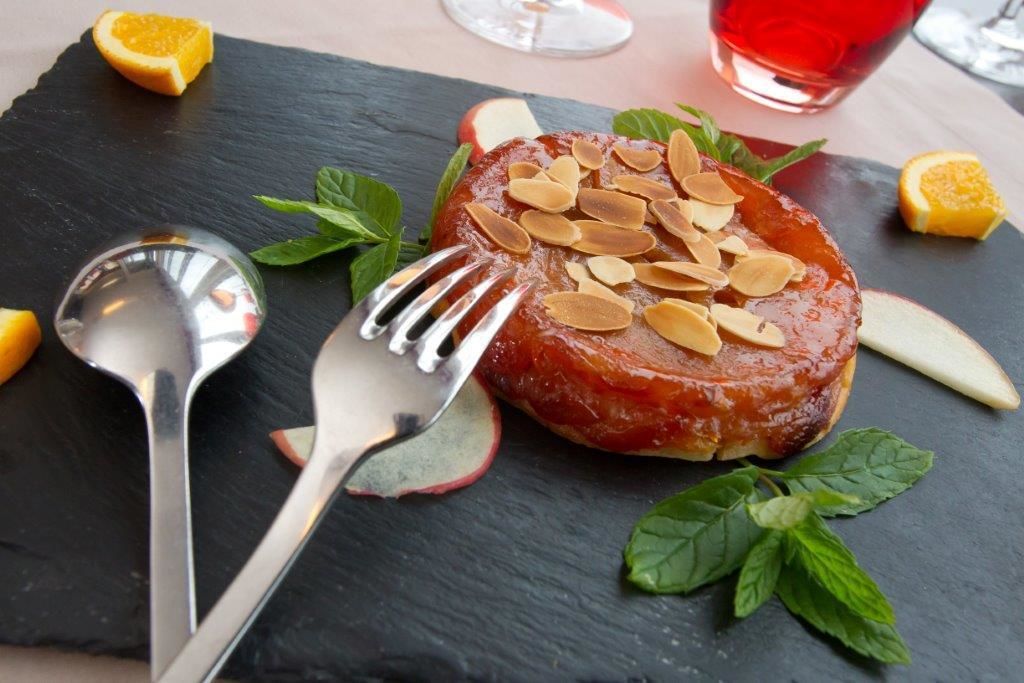 A dessert on a slate plate with a fork and spoon beside it.