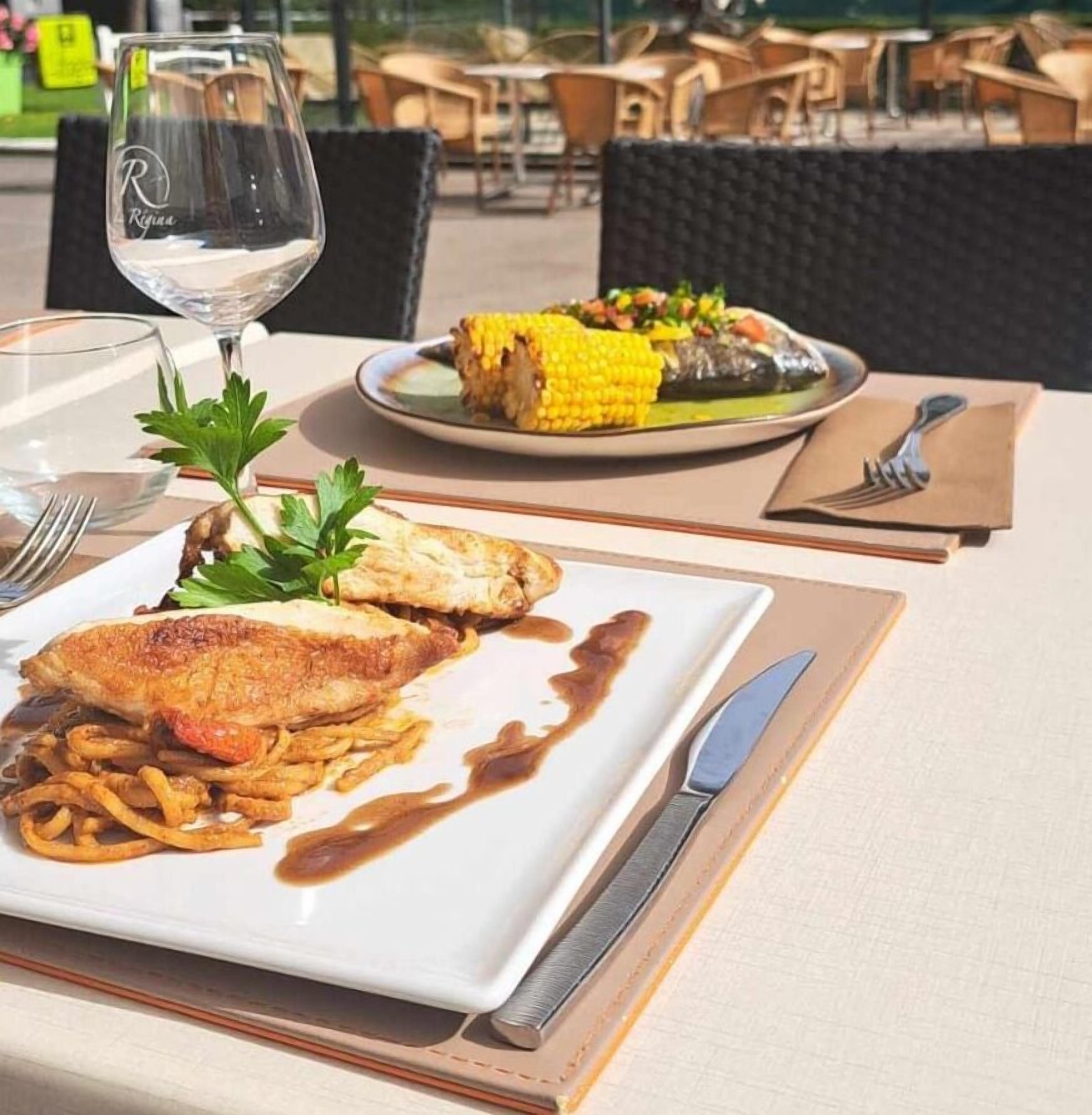 A dining table with a plate of food, a glass of water, and cutlery.