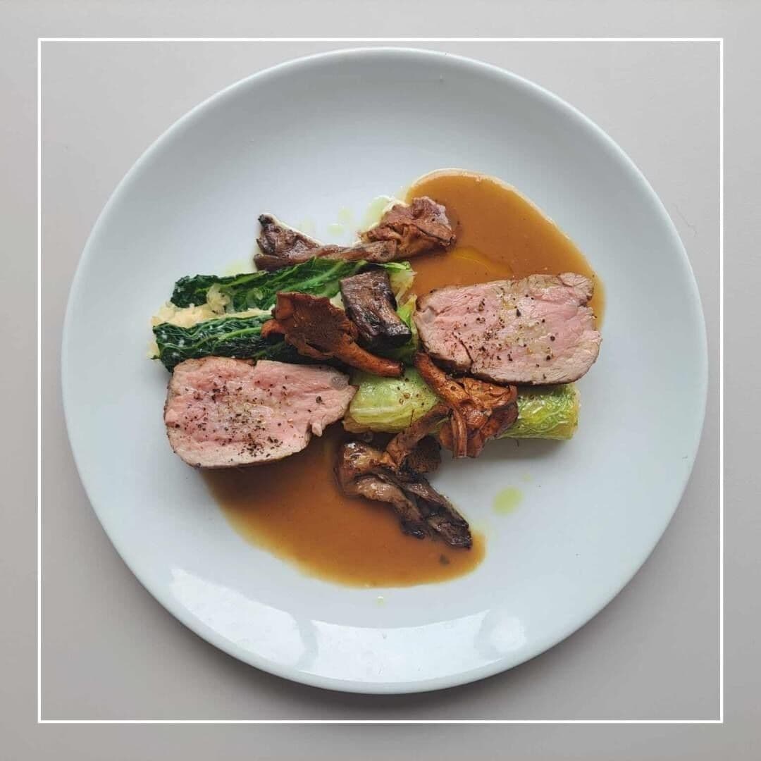 A plate of sliced meat with vegetables and a sauce.