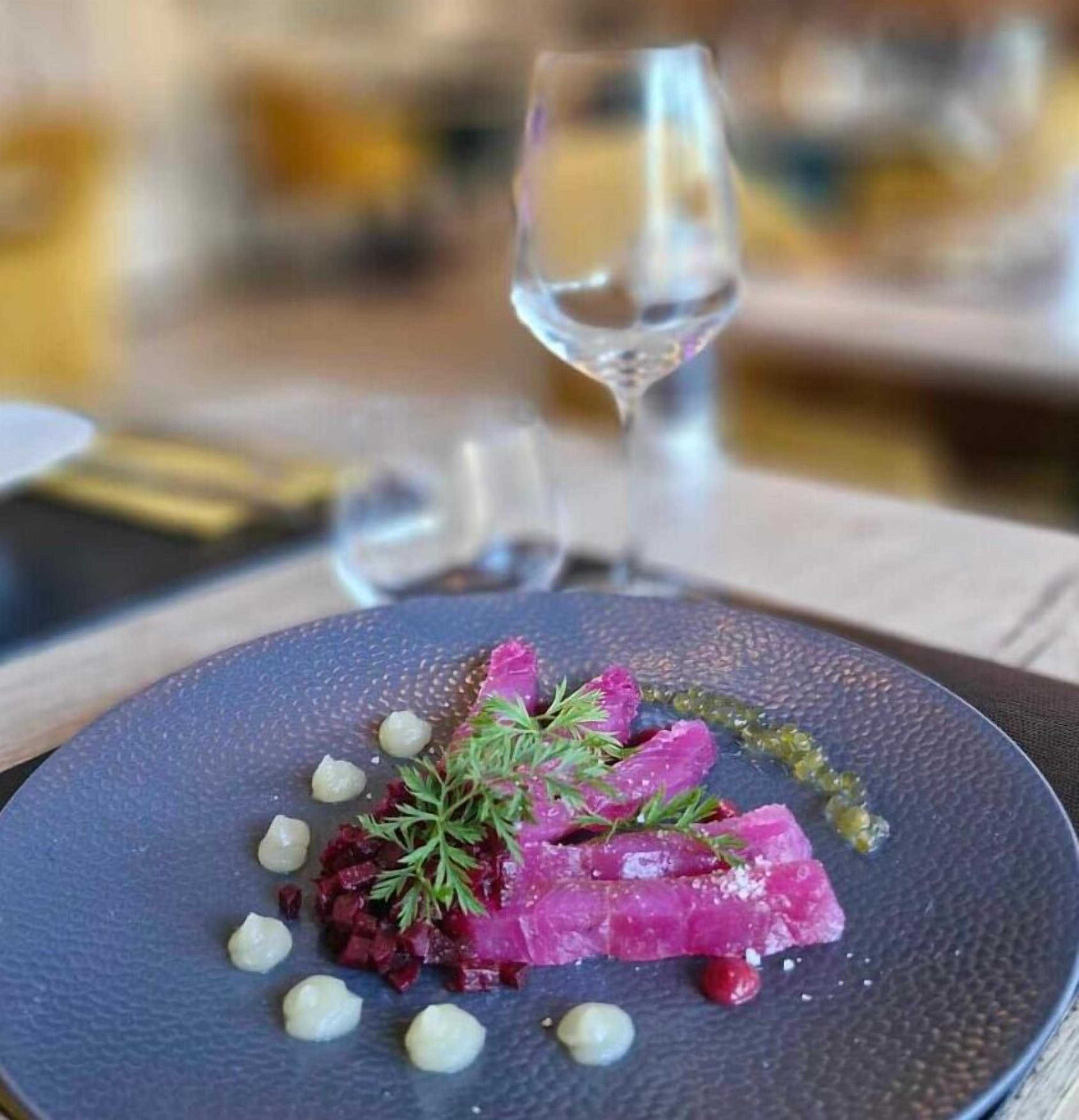 A plate of food with a glass of white wine on a table.