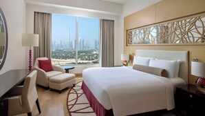 Habitación de hotel con una cama grande, un escritorio, una silla, vista a la ciudad y un adorno en la pared.