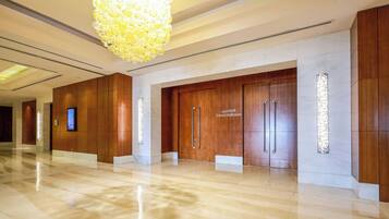 Un'hall dell'hotel con pavimento in marmo lucidato, un grande lampadario e porte in legno con la scritta 'Zabeel Ballroom'.