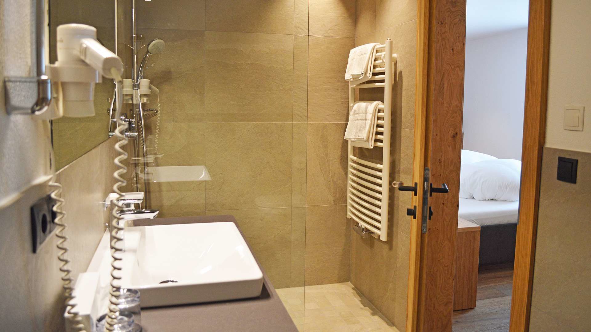 Un baño con lavamanos, toallero y ducha.