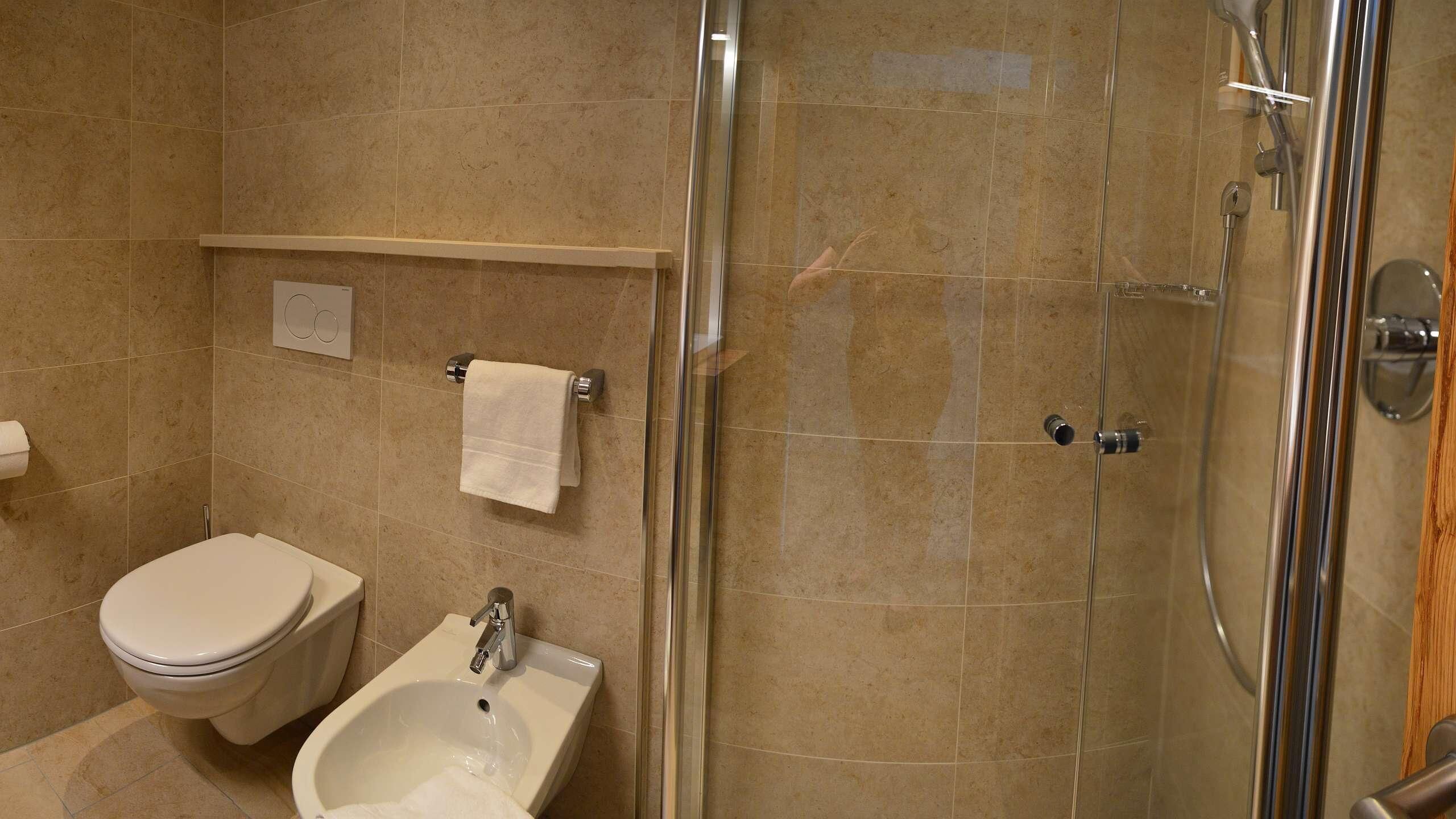 Un baño con inodoro, bidé y ducha con mampara de vidrio.