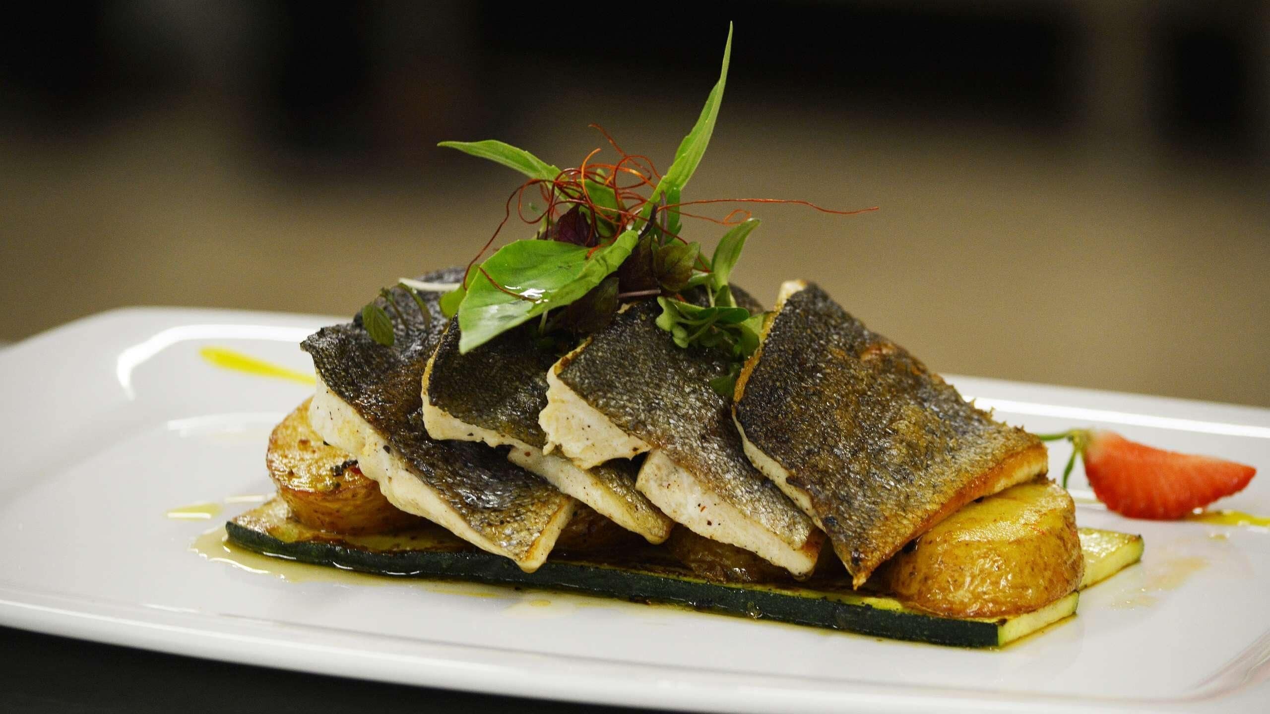 Un plato con pescado, verduras y una guarnición.