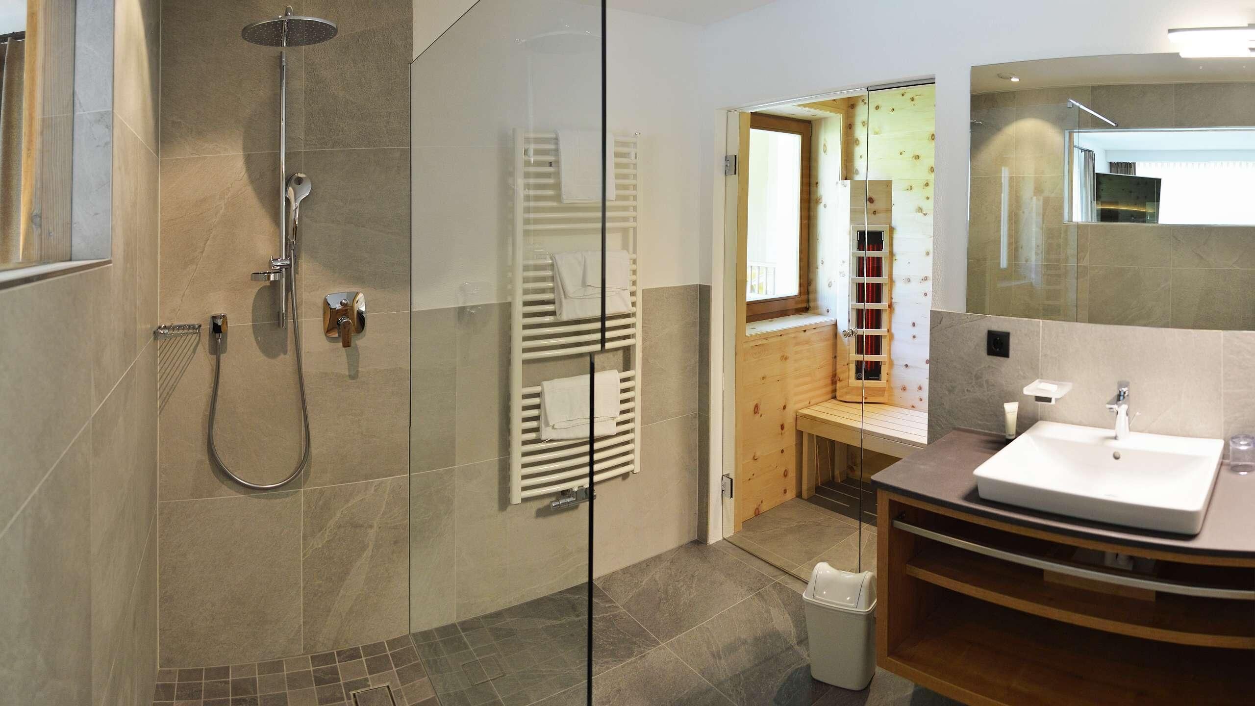A modern bathroom with a glass-enclosed shower, a wooden bench, a sink, and a mirror.