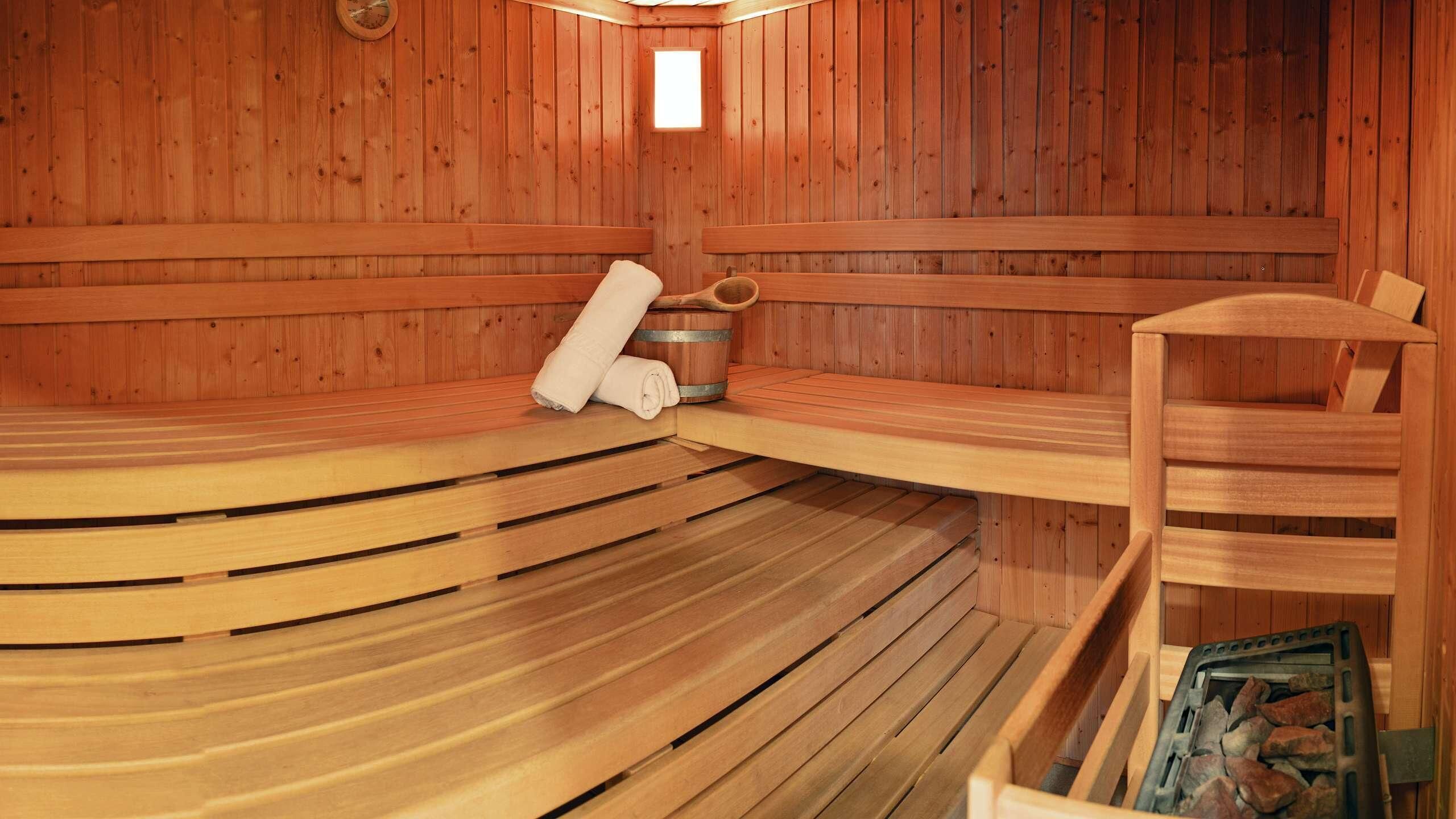 A wooden sauna with benches, a wooden bucket, and a towel.