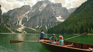 A wooden boat on a calm lake with mountains in the background. - Hotel Trenker (Braies)