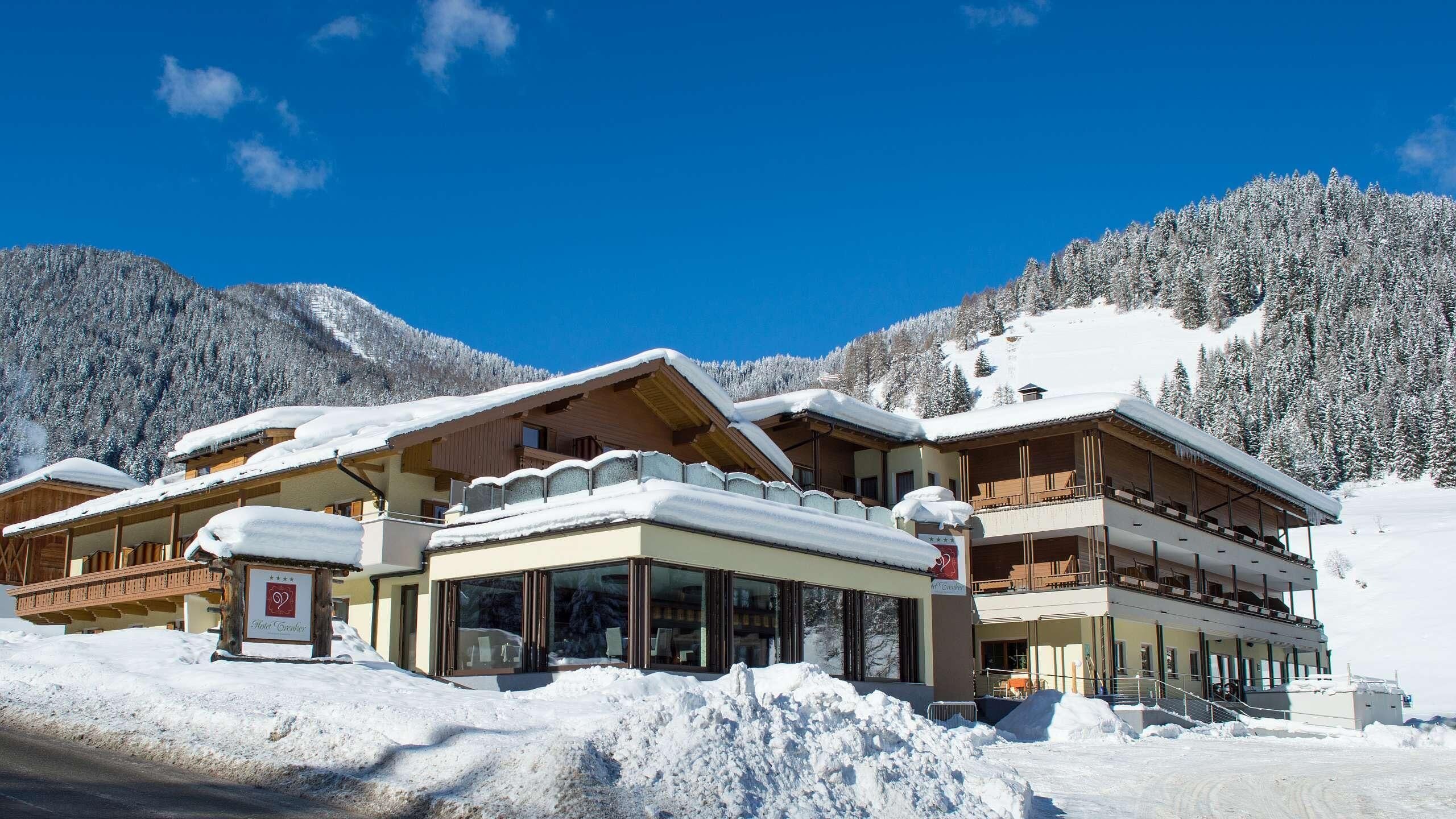 Un hotel con diversi piani, ampie finestre e una montagna innevata sullo sfondo.