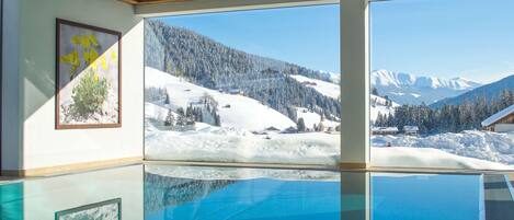 A room with a large window offering a view of a snowy mountain landscape.