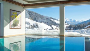 A room with a large window offering a view of a snowy mountain landscape. - Hotel Trenker (Braies)